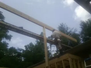Carpenter setting a ridge beam over a new addition frame — Ice Dam Removal by Roofing Brothers in Fairview